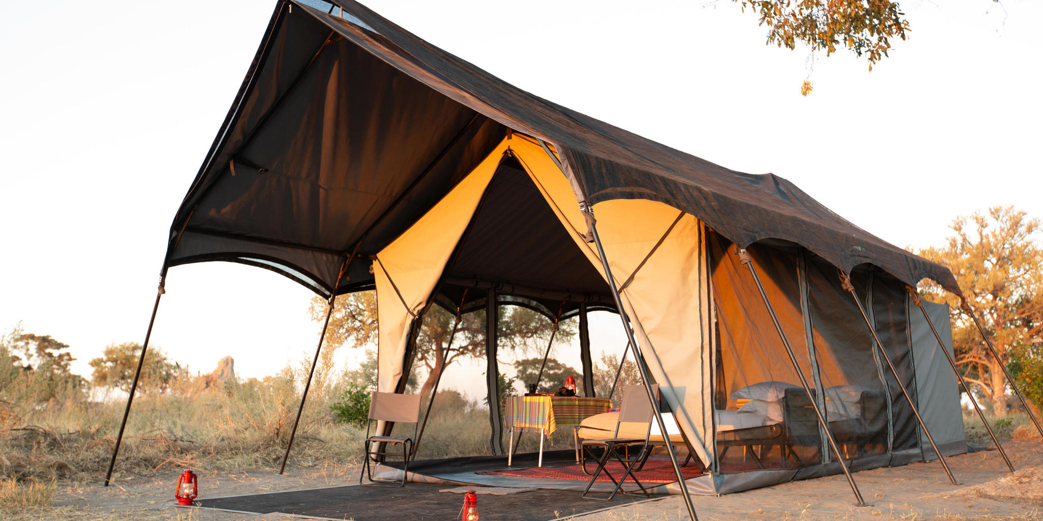 Guest Tent Exterior set up. Situated in the middle of dry vegetation with warm sunrays reflecting off tent material.