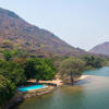 A aerial view of a lodge pool along Lake Malawi. A large lake surrounded by dry vegetation. 
