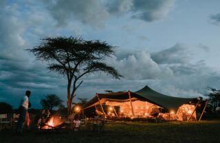 Guests around a campfire at a luxury tented camp, Serengeti, Tanzania, Yellow Zebra Safaris