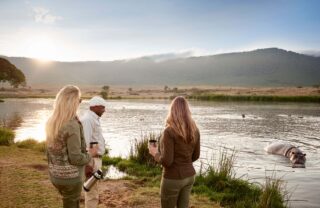Guests with guide beside a lake with hippos, Ngorongoro, Tanzania, Yellow Zebra Safaris