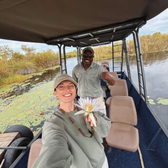 kate and her guide stand on a boat in the okavango delta, botswana