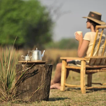 A guest drinks coffee outside admiring the view - Yellow Zebra Safari