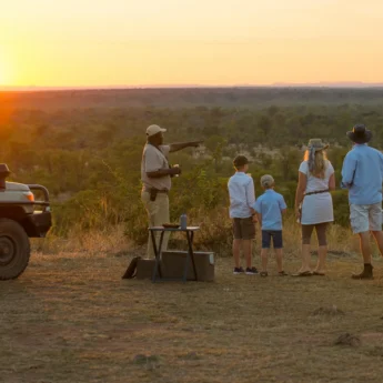 A family enjoys the sunset view whilst having sundowners on a ridge, Luangwa Safari House, South Luangwa, Zambia - Yellow Zebra Safari
