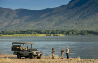 Guests and guide enjoy a drink alongside the water, Nyamatusi Camp, Zimbabwe - Yellow Zebra Safaris