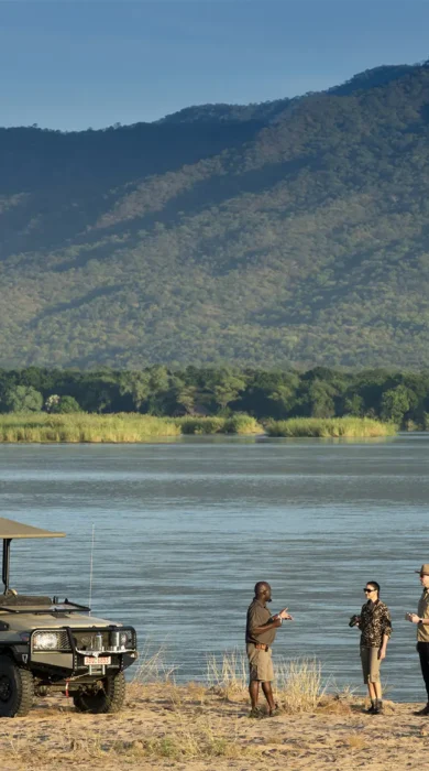Guests and guide enjoy a drink alongside the water, Nyamatusi Camp, Zimbabwe - Yellow Zebra Safaris