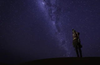 A starry night sky in kunene river and a woman is out stargazing, Namibia - Yellow Zebra Safaris