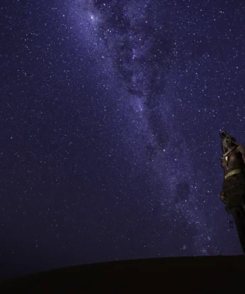 A starry night sky in kunene river and a woman is out stargazing, Namibia - Yellow Zebra Safaris