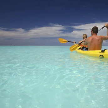 A man and woman share a two-person kayak in turquoise ocean, &Beyond Mnemba Island, Zanzibar - Yellow Zebra Safari