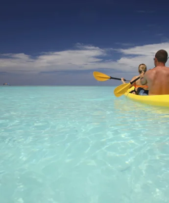 A man and woman share a two-person kayak in turquoise ocean, &Beyond Mnemba Island, Zanzibar - Yellow Zebra Safari