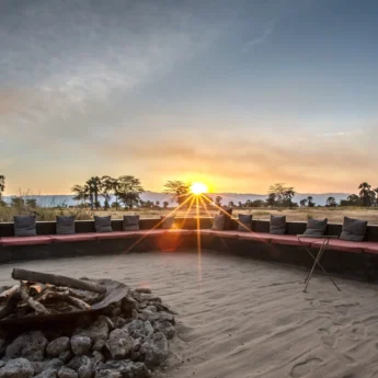 The setting sun shines over a fire pit, Chem Chem Lodge, Tanzania - Yellow Zebra Safari