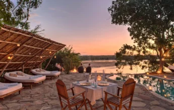An outdoor patio area with a plunge pool, sun loungers and a table set for dinner, Tanzania - Yellow Zebra Safari