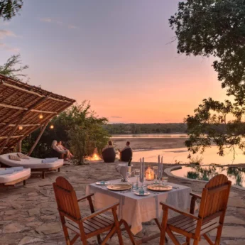 An outdoor patio area with a plunge pool, sun loungers and a table set for dinner, Tanzania - Yellow Zebra Safari