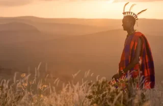 A man in traditional Maasai dress at sunset, Sirikoi, Kenya - Yellow Zebra Safaris