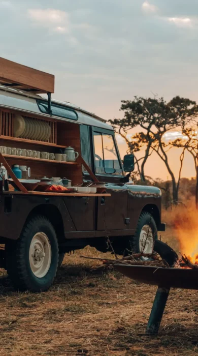 A fire is lit and a safari truck is transformed into a bar ready for Bush Brunch, Wayo Serengeti Green Camp, Tanzania - Yellow Zebra Safari