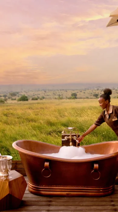 A staff member fills up an outdoor bubble bath on a deck which overlooks the plains, One Nature Mara River, Serengeti, Tanzania - Yellow Zebra Safari