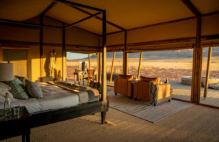 An interior view of the four poster bed which looks out onto the dunes, Wolwedans Plains Camp, Namibia - Yellow Zebra Safaris