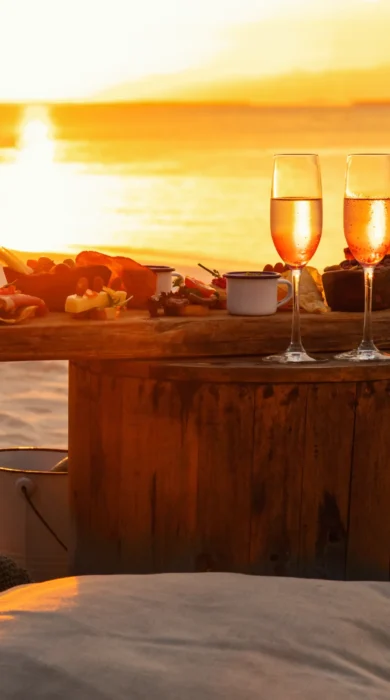 Sun shines through champagne glasses on a table on the beach, Zuri Zanzibar, Tanzania - Yellow Zebra Safari