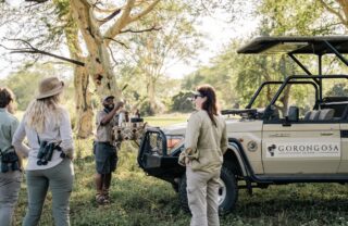 Guests and guide stand around the safari vehicle, Muzimu Lodge, Gorongosa, Mozambique - Yellow Zebra Safaris