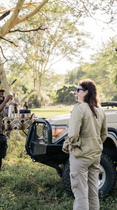 Guests and guide stand around the safari vehicle, Muzimu Lodge, Gorongosa, Mozambique - Yellow Zebra Safaris