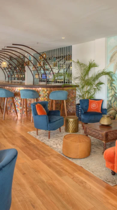 Lounge and bar with brightly coloured blue and orange couches at Latitude 0 Degrees, Kampala, Uganda - Yellow Zebra Safaris