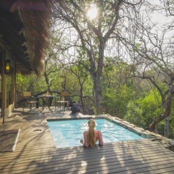 A woman rests in a plunge pool outside her room, Jabulani, Kruger National Park, South Africa - Yellow Zebra Safari